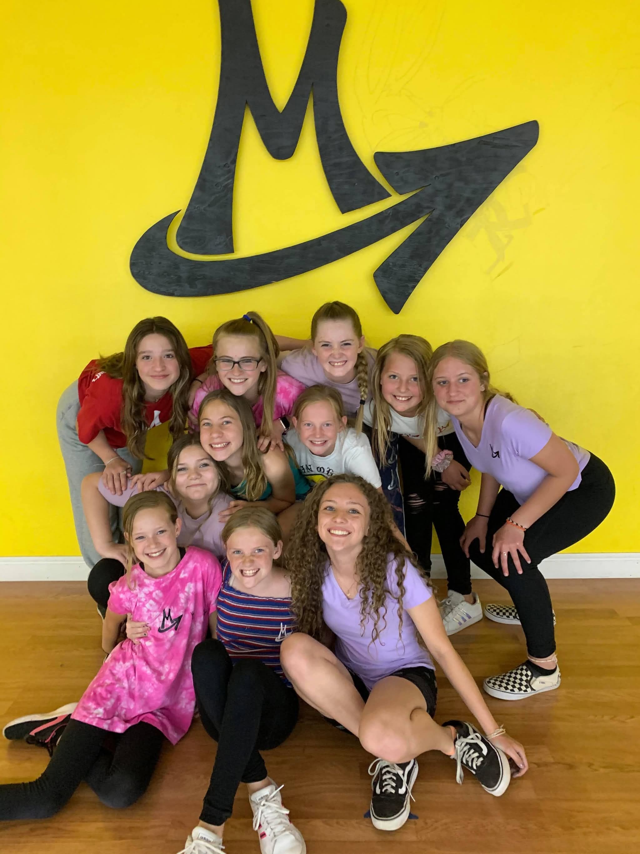 The Cash Money Hip Hop dancers piled together on the studio floor, laughing, beneath the Main Ohana logo