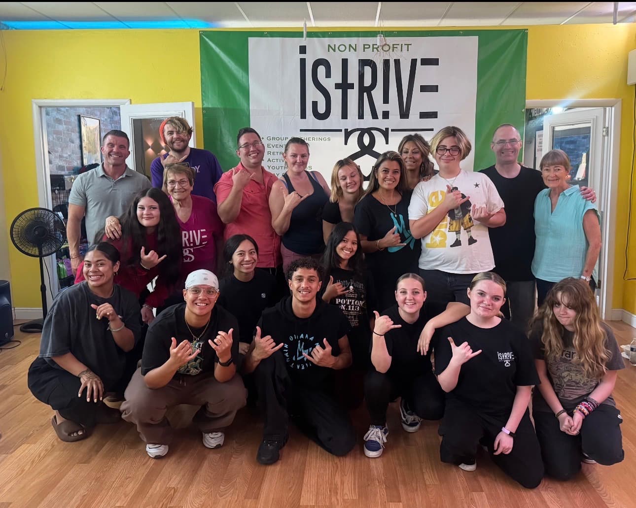 The iSTRIVE community group gathered in front of the iSTRIVE nonprofit banner