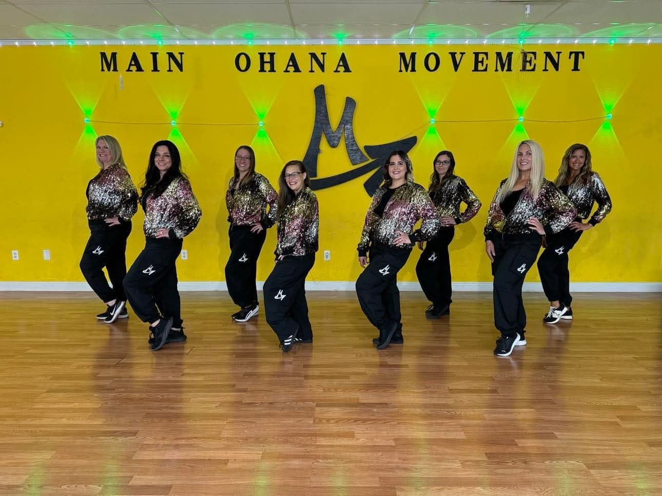 The M.O.M. Squad in matching sequined jackets and black joggers, posed in a line under the Main Ohana Movement logo